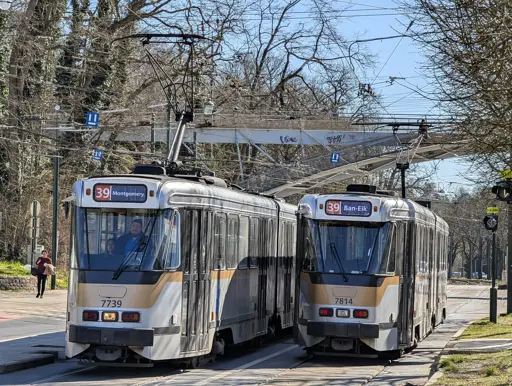 Two trams of the PCC type passing by each other. in the background trees and a bridge over the street and the tracks